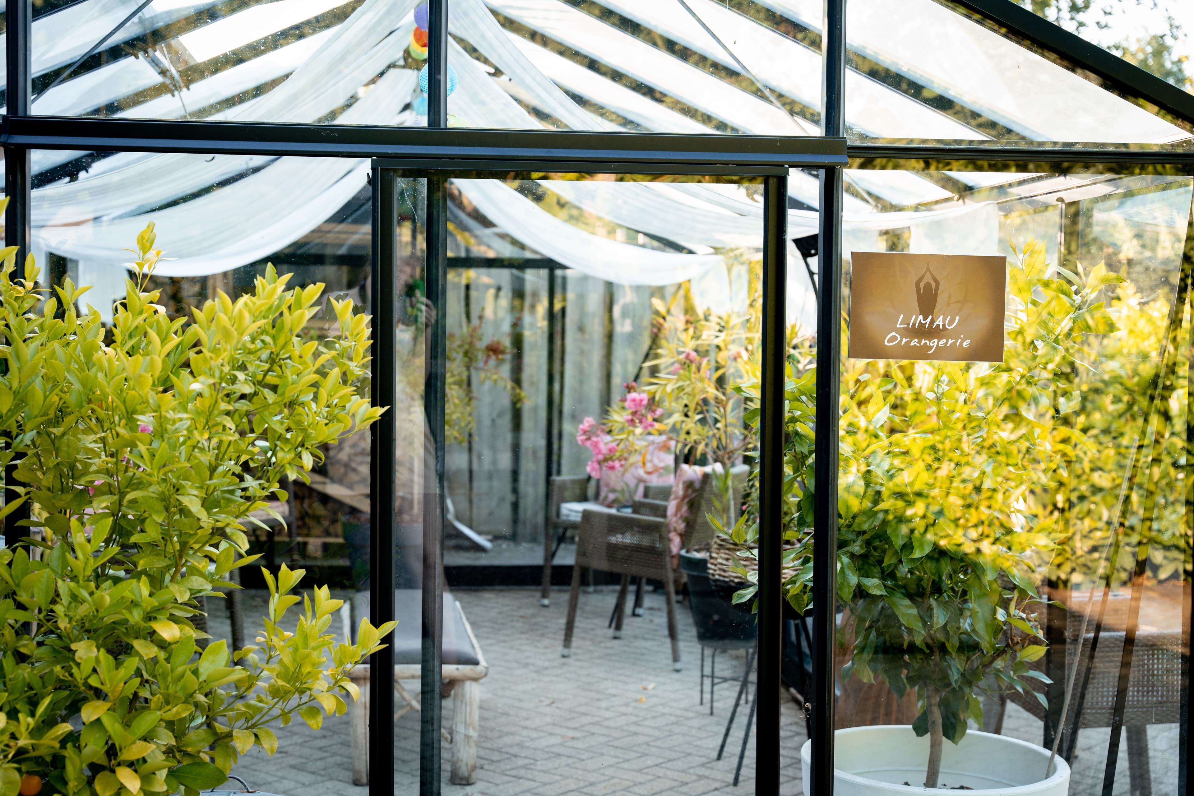 Glazen kas met zitplaatsen in de buitenruimte van Thermen Binnenmaas